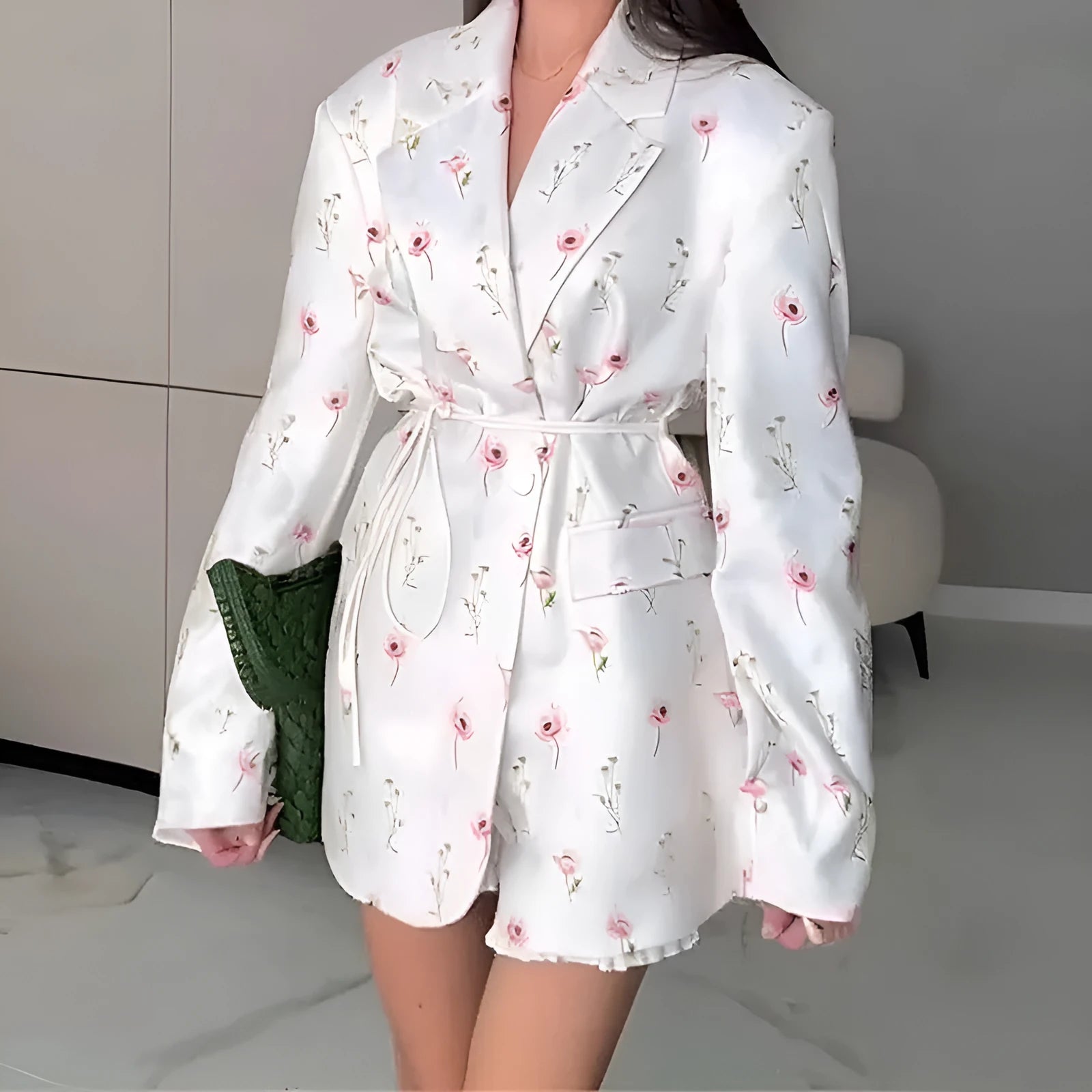 White floral print suit jacket with a lace-up detail at the waist on a hanger.