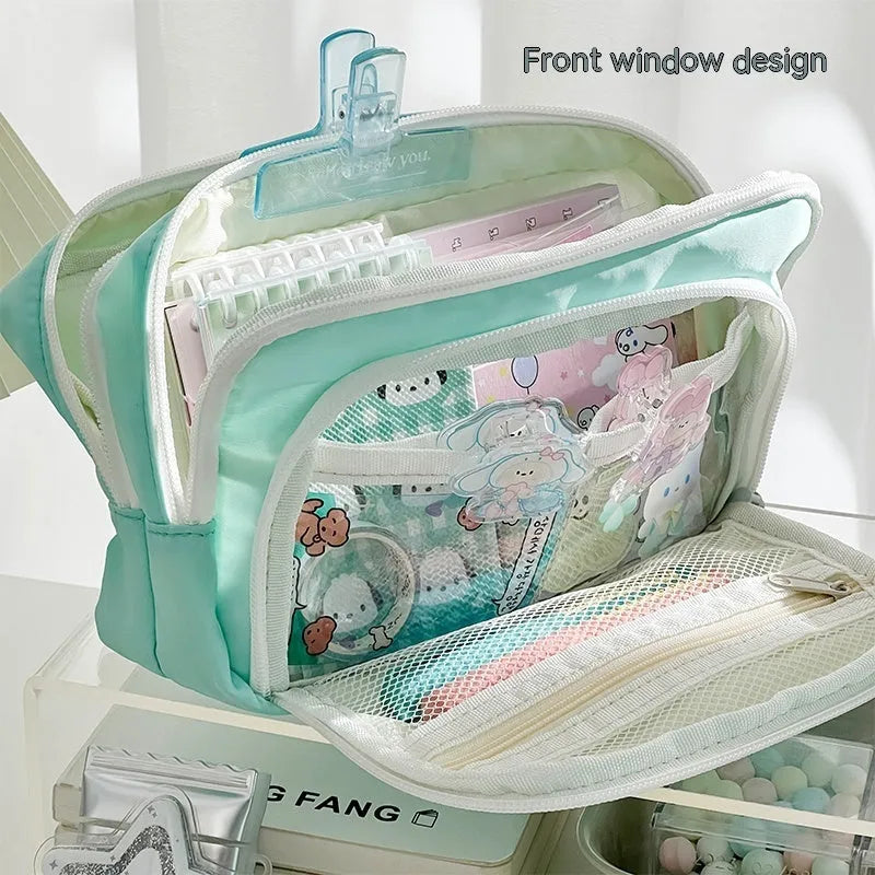 Double layer pencil case in pink with a gift handle, shown next to pens and pencils.