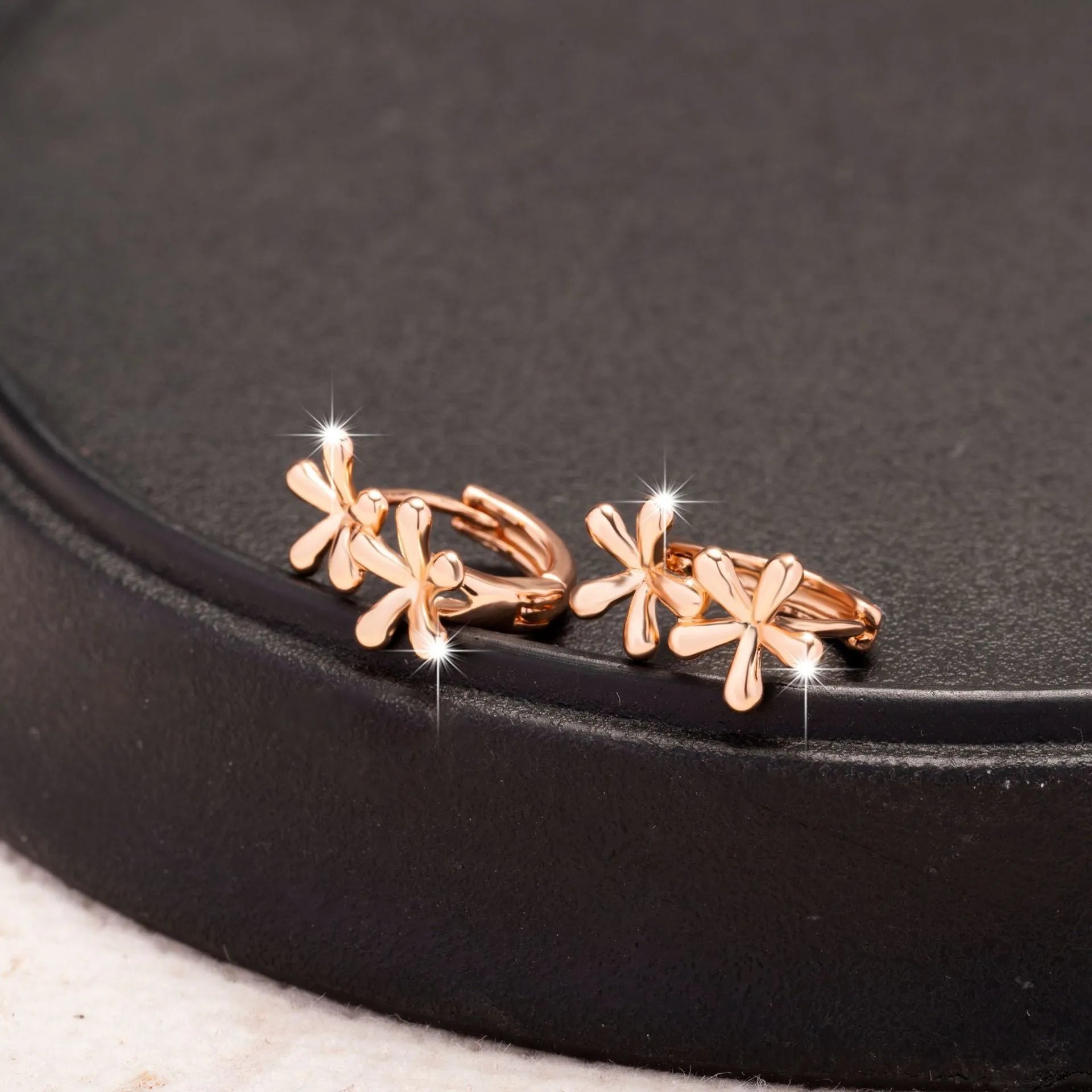 Rose gold electroplated earrings with a waterdrop shape and detailed floral petal etching on a white background.