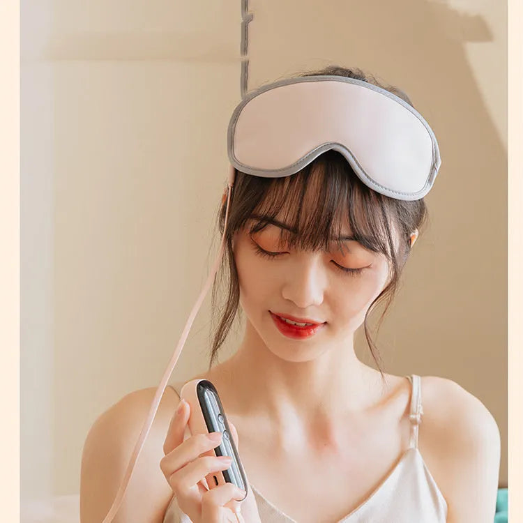 Pink portable eye SPA mask with steam and vibration massage functions on a grey background.