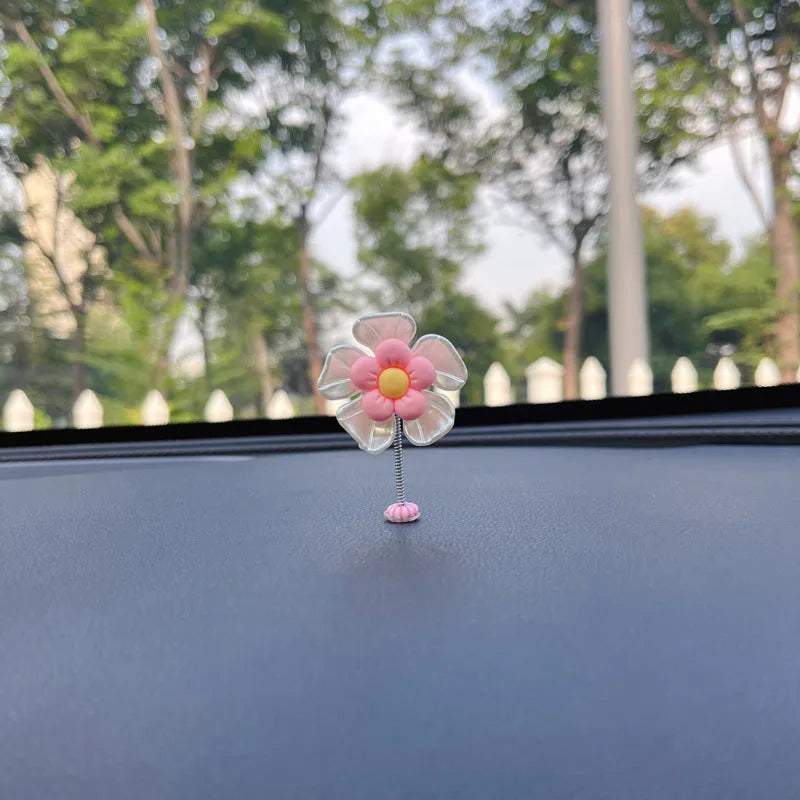 Small colourful plastic swing ornament for car dashboard, shown in multiple colour options.