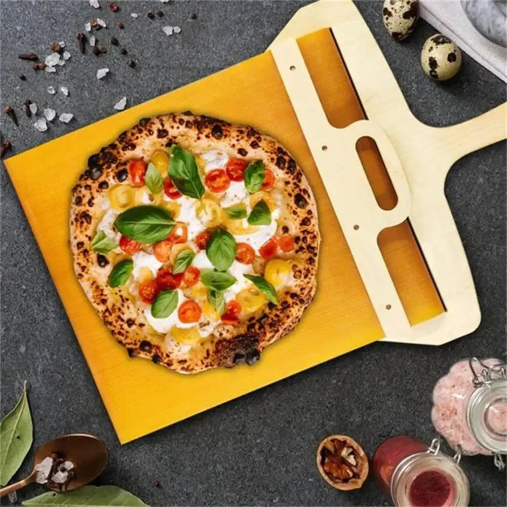 White plastic pizza transfer shovel on a kitchen counter, showing its flat board surface and handle with hanging hole.