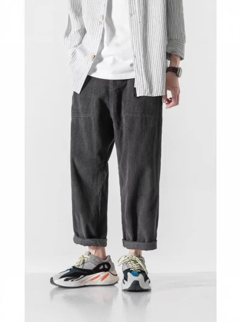Man wearing loose straight leg casual trousers in dark grey, showing tapered fit and wide leg opening.