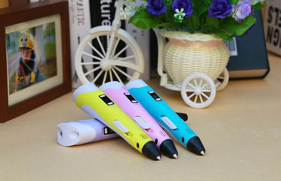 Yellow 3D printing pen with 12 colour PLA filament spools and UK power adapter on a white background