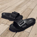 A pair of women's grey blue buckle slipper sandals with an adjustable strap on a soft EVA sole.