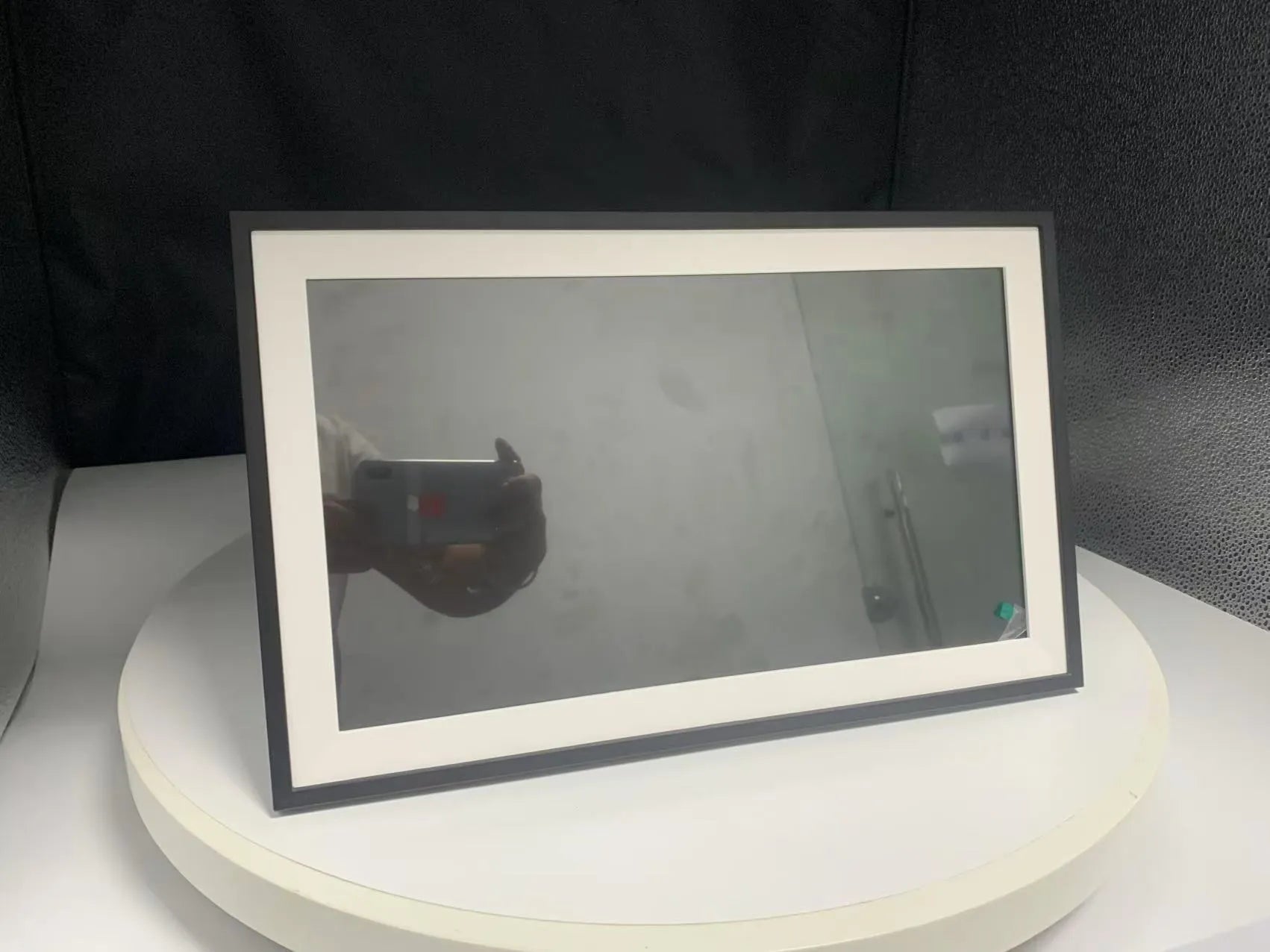 White 15.6 inch smart digital photo frame with wall bracket on a wooden table.