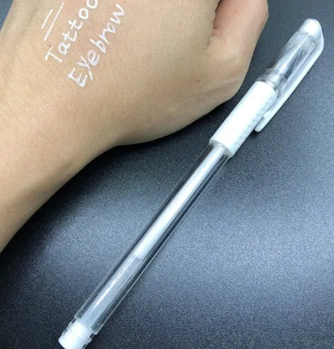 White hard pen calligraphy pen with cap closure on a dark surface showing white ink lines