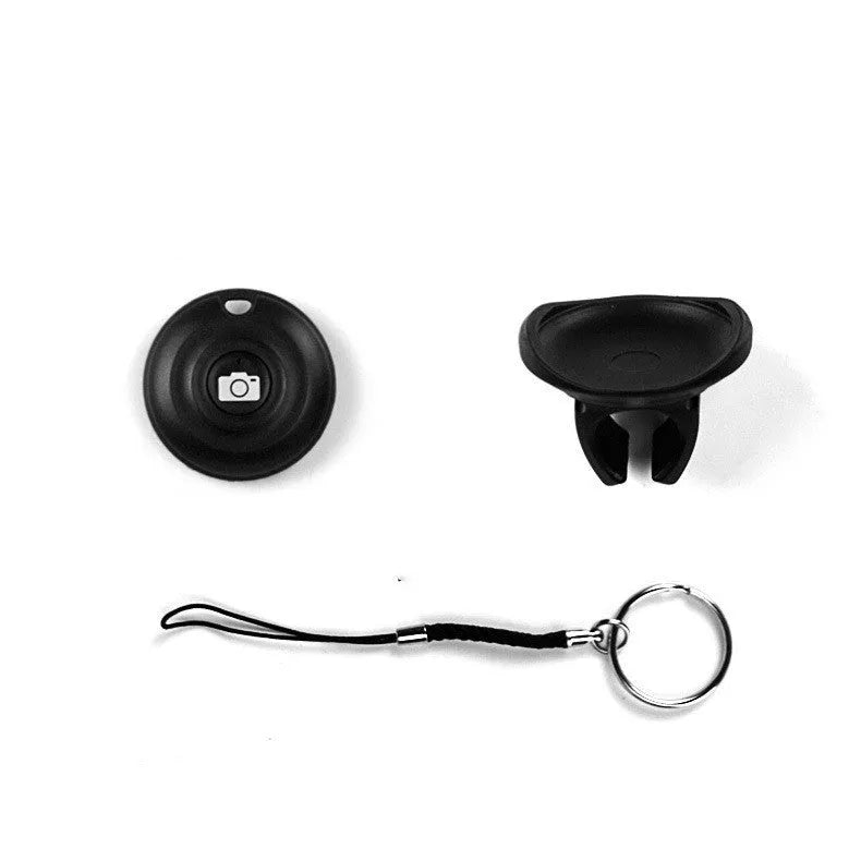 Small black Bluetooth selfie remote on a palm, showcasing its compact size and single button.