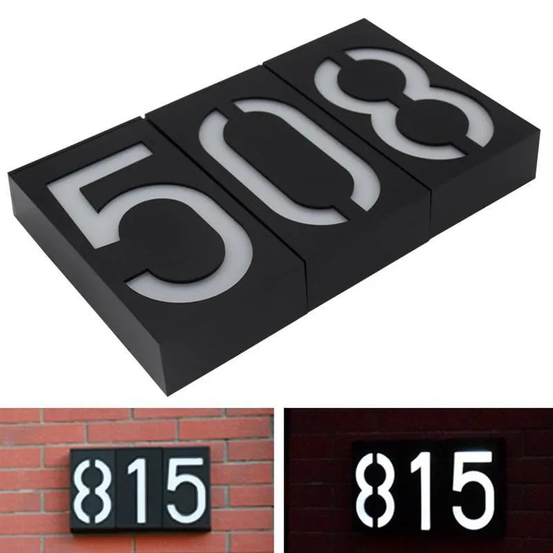 White solar-powered house number light with visible solar panel and LEDs, mounted on a wall.