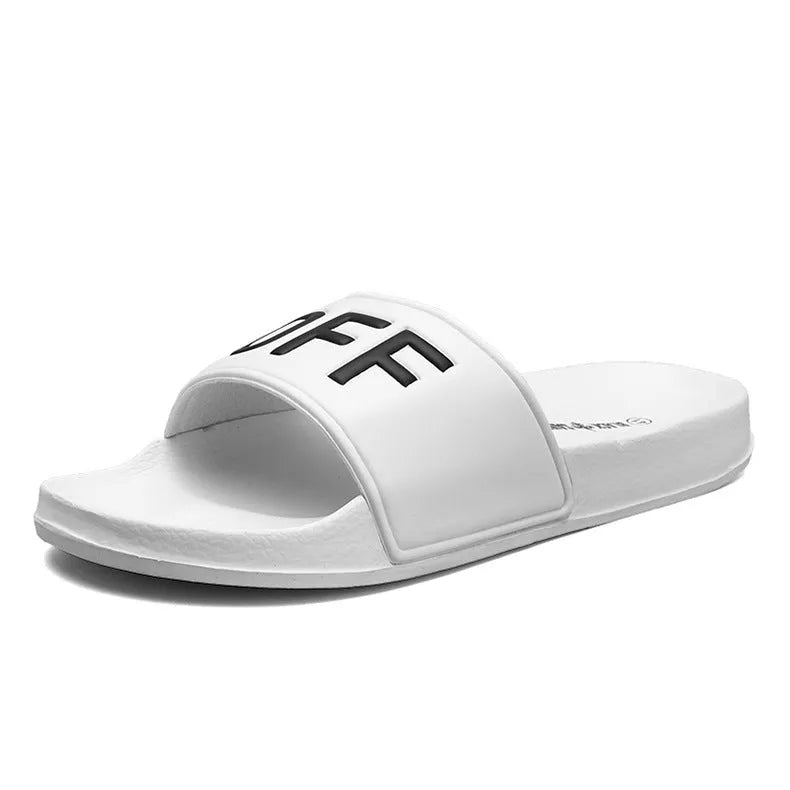 A pair of black open-toe men's slippers with a visible rubber sole, shown on a wooden floor.