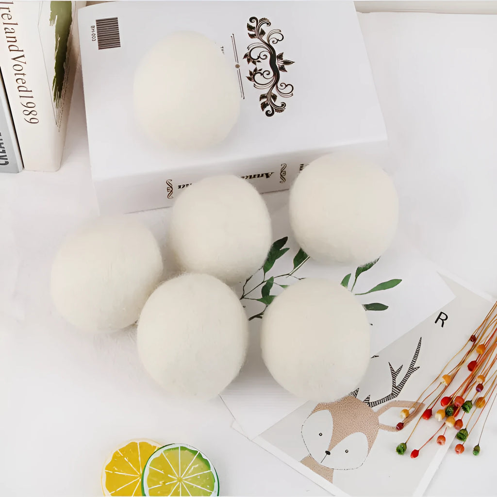 Set of wool laundry drying balls next to cotton storage bag for tumble dryers