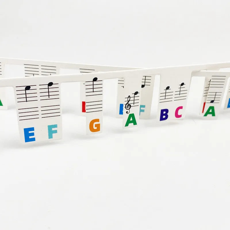 White cardboard piano keyboard stickers showing staff notation for 88 keys, with black notes and colour note bar options