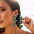 Oil dripping four petal flower earrings in orange resin on a white background
