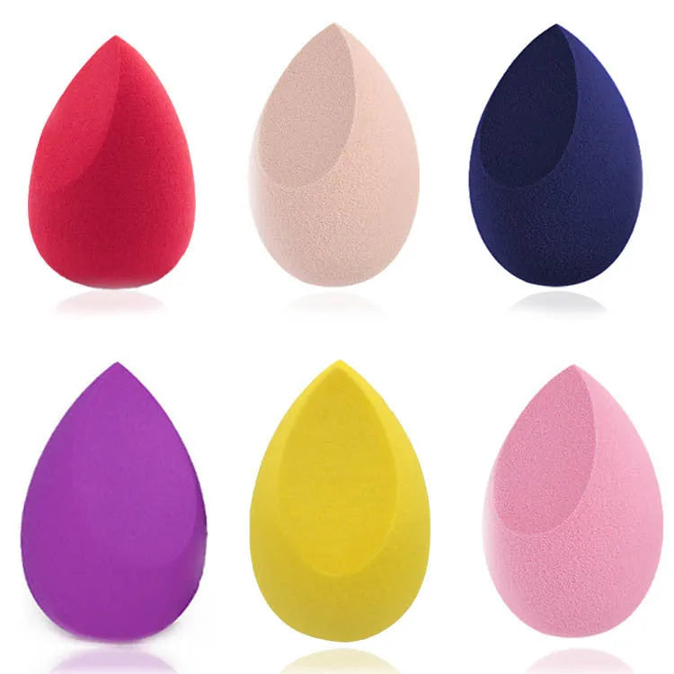 Set of seven coloured makeup sponges in different shapes on a pink background