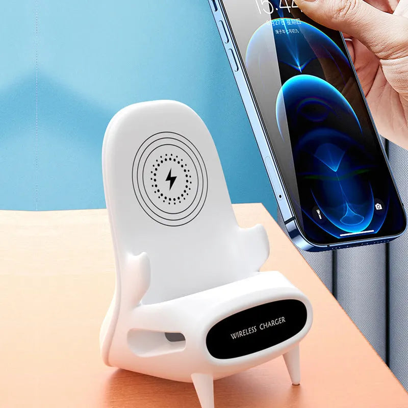 White mini chair shaped wireless charging stand holding a mobile phone on a desk.
