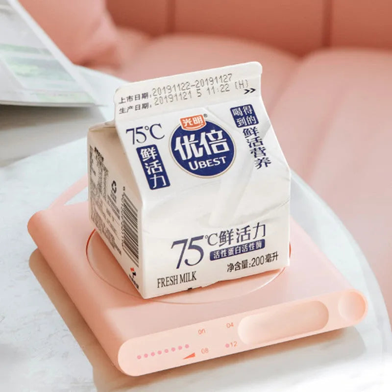 Pink and white USB-powered heating cup pad with mechanical timer control for keeping mugs warm.