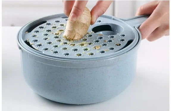 Blue 8-in-1 mandoline slicer with stainless steel blades, container, hand protector, and drain basket on kitchen counter