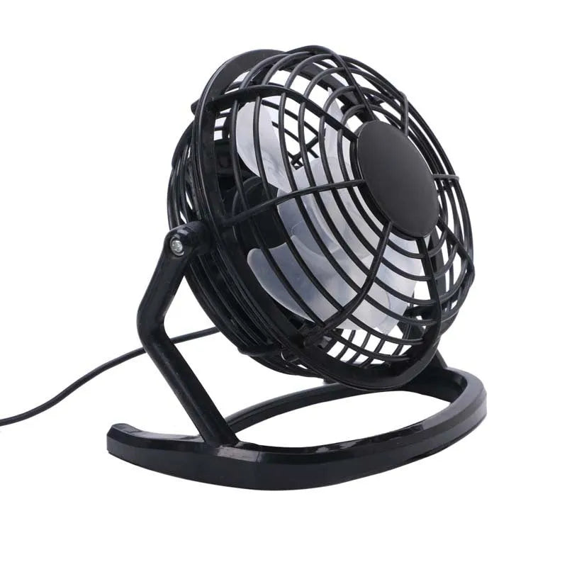 Small black and white USB desktop fan with adjustable stand on a desk next to a laptop.