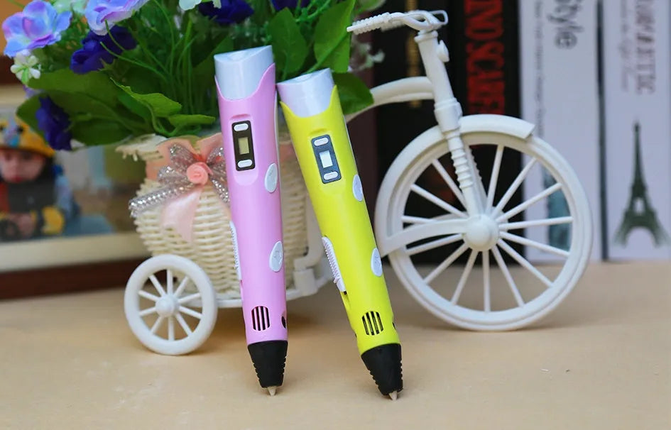 Yellow 3D printing pen with 12 colour PLA filament spools and UK power adapter on a white background