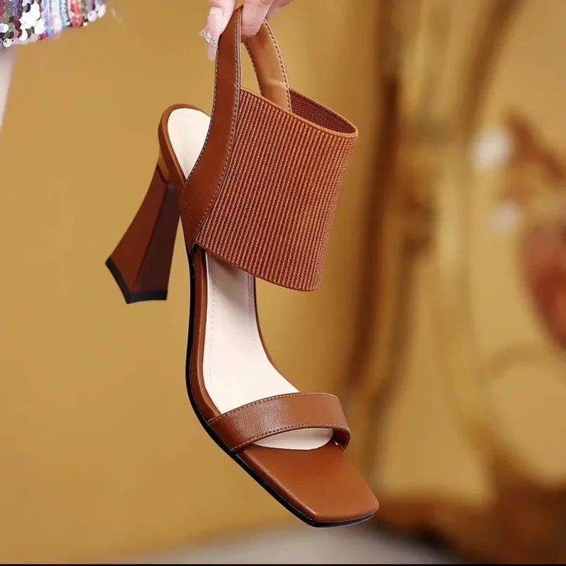 Women's black high heel sandals with an elastic strap across the foot and a rubber sole.