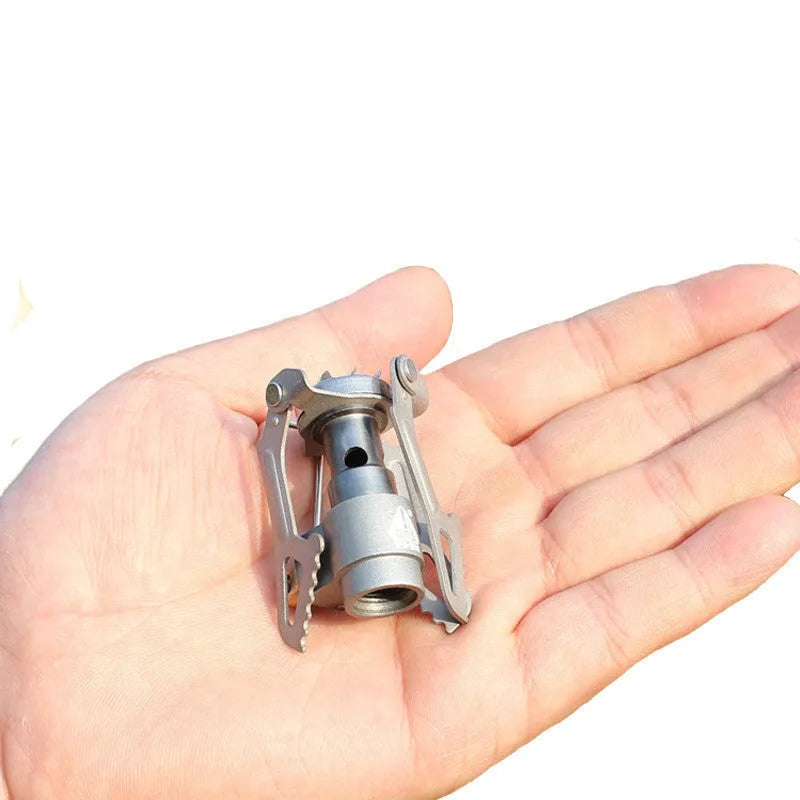 Compact silver portable camping stove with a one-piece burner, using a small green propane gas canister.