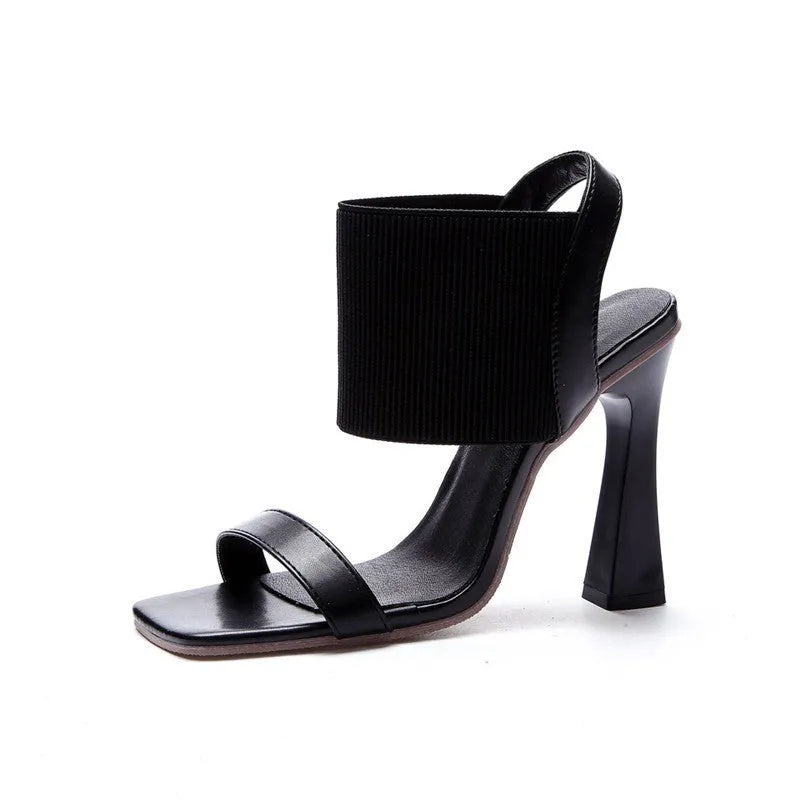 Women's black high heel sandals with an elastic strap across the foot and a rubber sole.