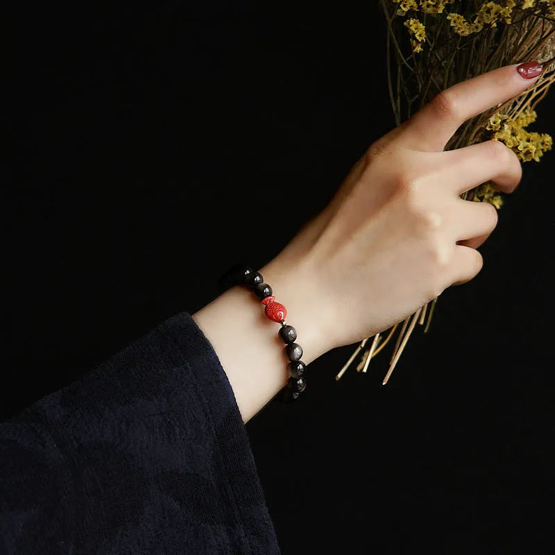Natural obsidian bracelet with round cinnabar beads in three size options on a wrist
