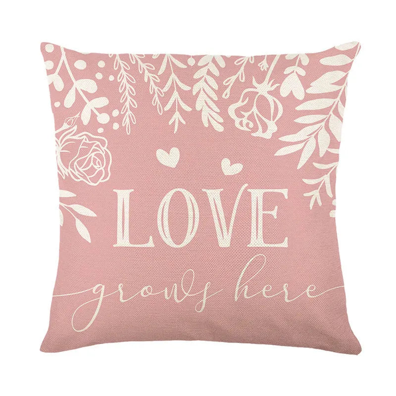 Square red and black plaid pillow cover with white heart shapes, resting on a grey sofa.