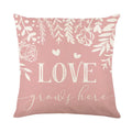 Square red and black plaid pillow cover with white heart shapes, resting on a grey sofa.