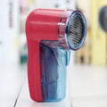 Compact white handheld electric lint remover for clothing, showing fabric shaving head.