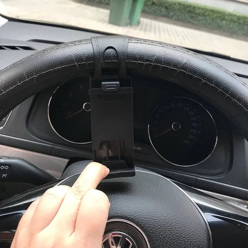 Black universal steering wheel phone clip holder with silicone pad mounted on a car steering wheel.