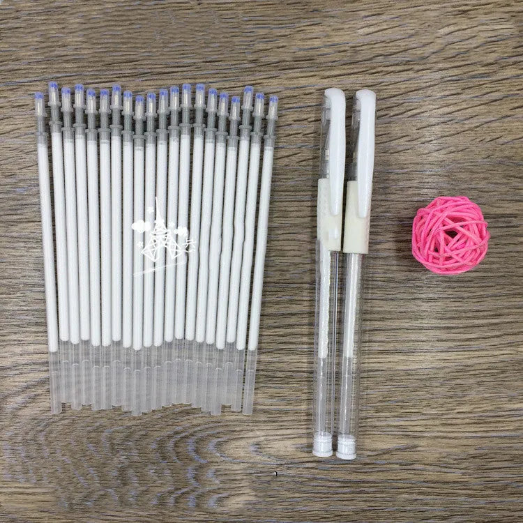 White hard pen calligraphy pen with cap closure on a dark surface showing white ink lines