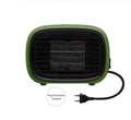 Small green portable ceramic fan heater on a desk showing its compact size.