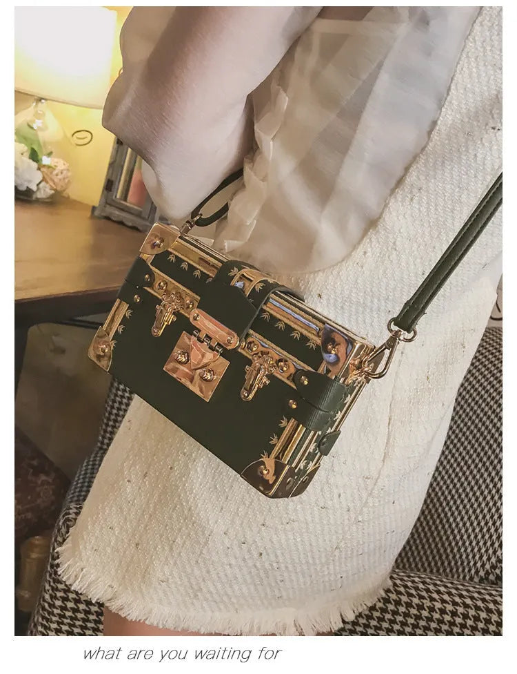 Hard-sided black women's shoulder bag with a flap closure, adjustable strap, and decorative metal rivets.