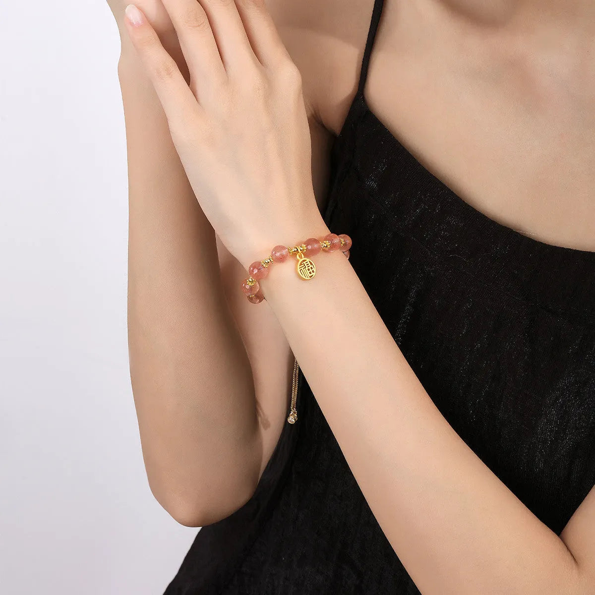 Women's strawberry quartz bracelet with a geometric fu character charm on an electroplated chain.