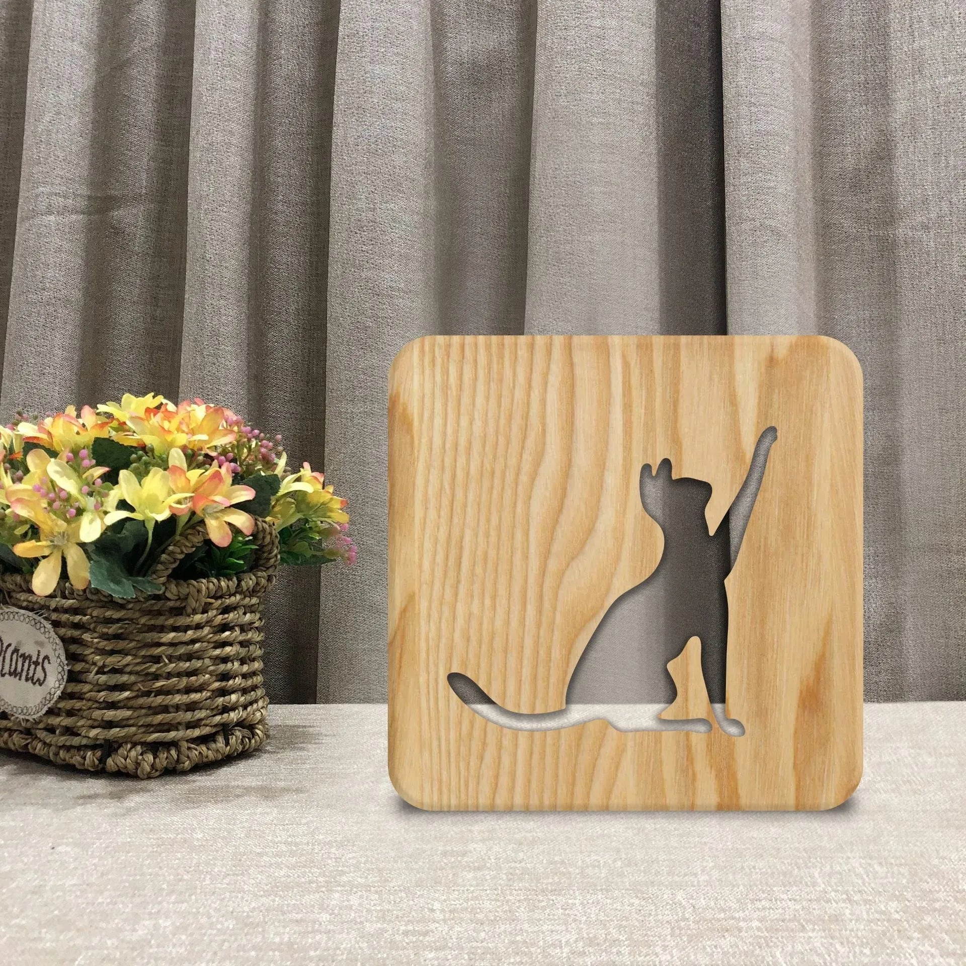 Square solid wood night light with hollow 3D cat silhouette, shown lit with warm glow.