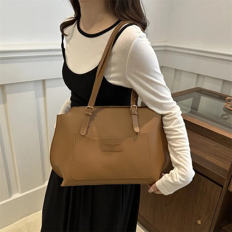 Women's square PU tote bag in black with double straps, showing external sandwich pocket and sewing line detail.