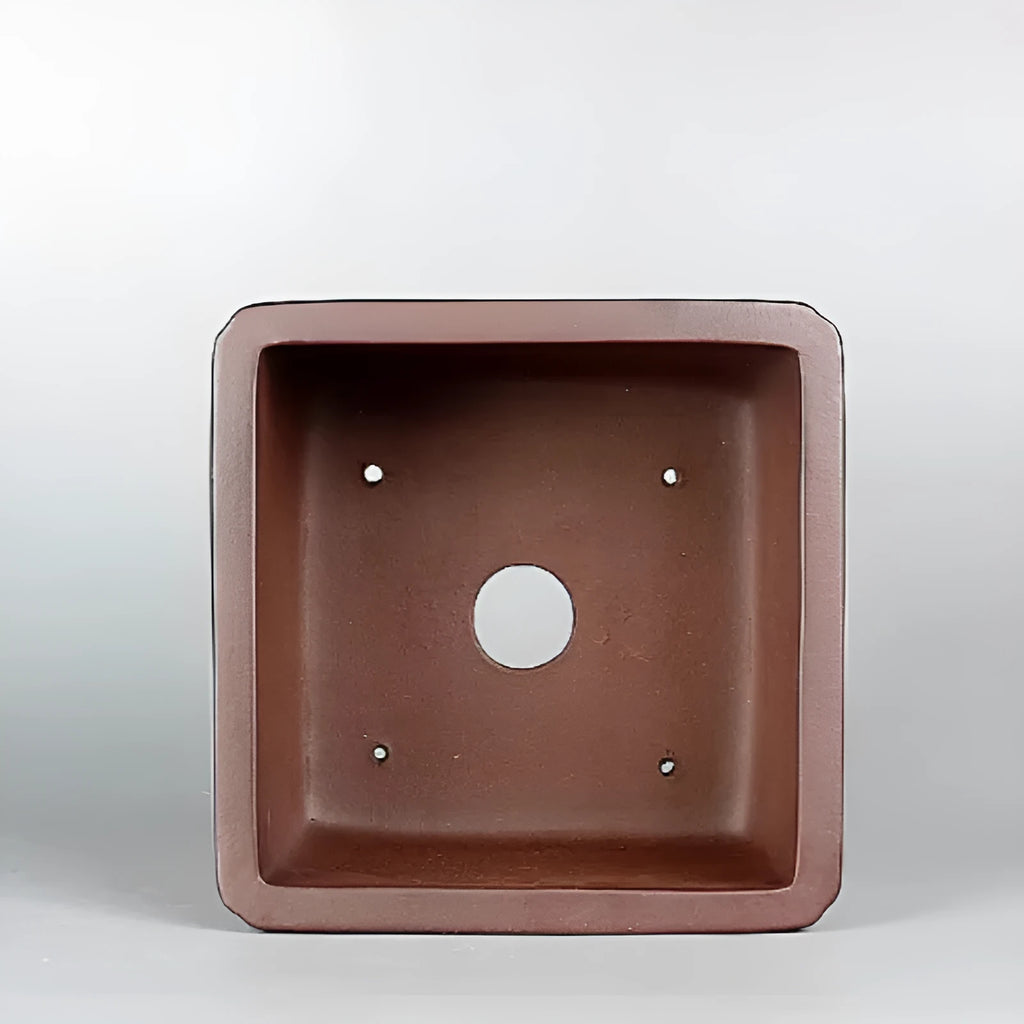Handmade brown antique-style purple clay square flower pot on a surface.