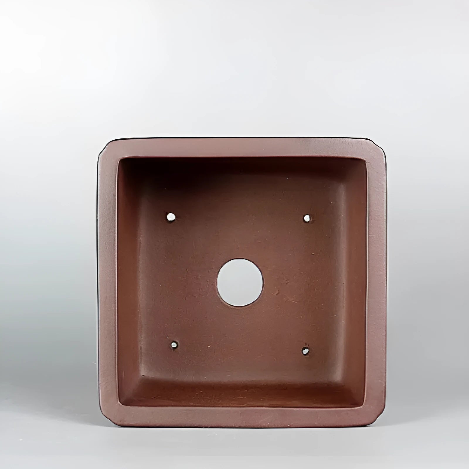 Handmade brown antique-style purple clay square flower pot on a surface.