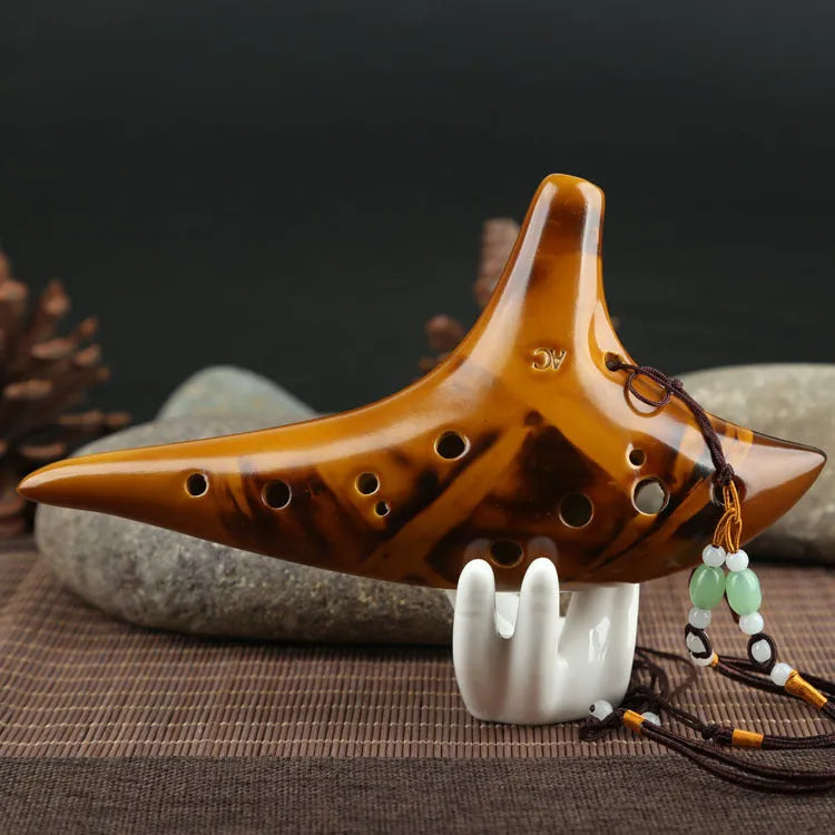 Yellow 12-hole ceramic Alto C ocarina with smoldering finish and lanyard on a surface