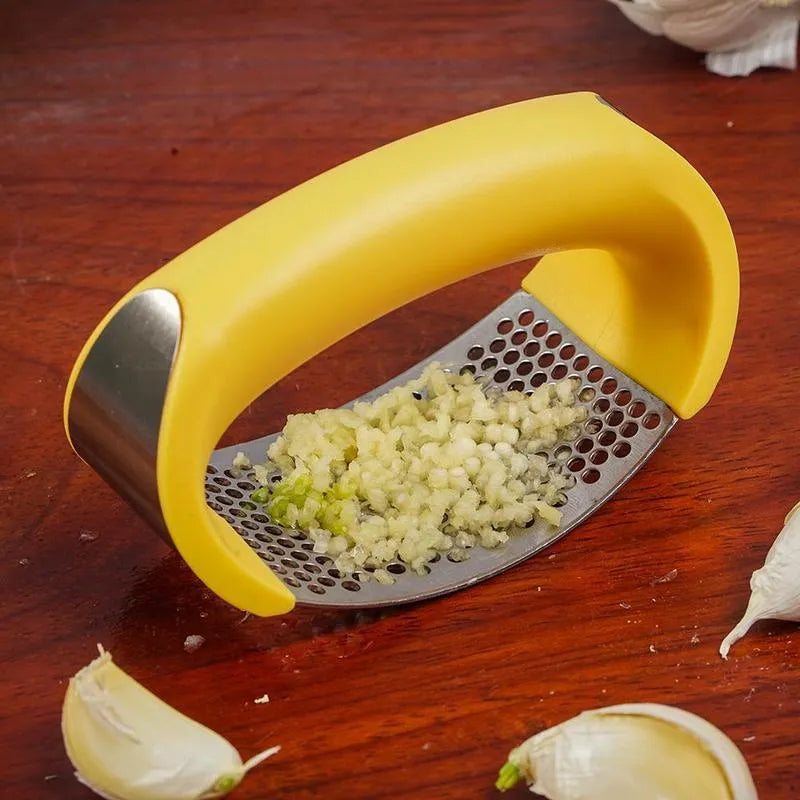 Stainless steel garlic press with coloured ergonomic handle on a kitchen counter.