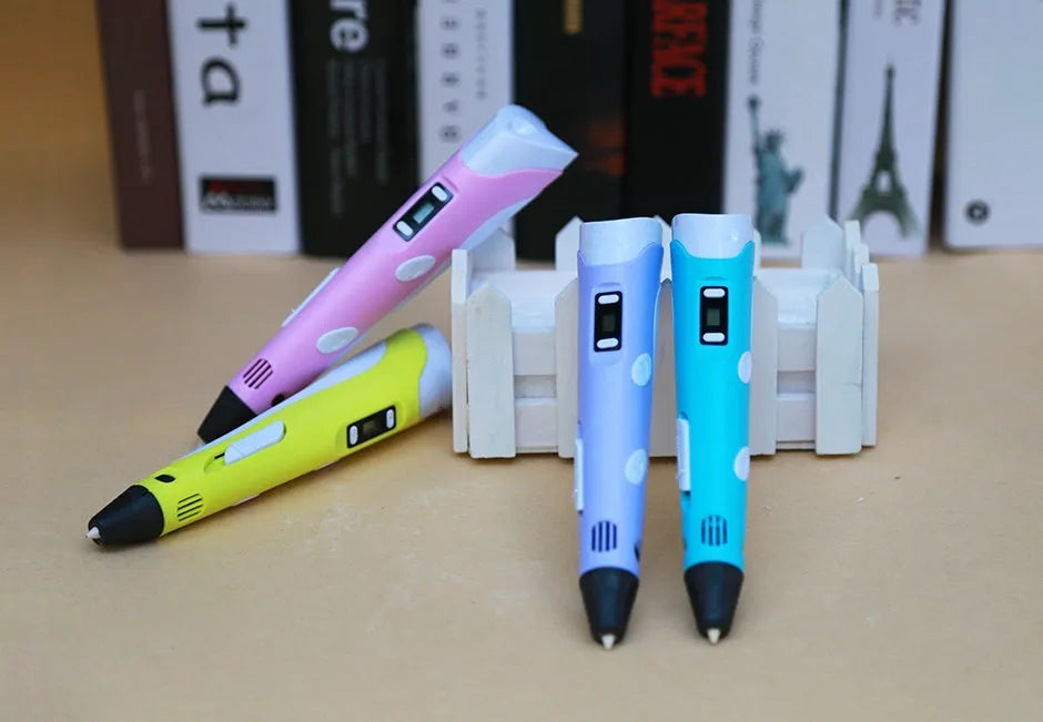 Yellow 3D printing pen with 12 colour PLA filament spools and UK power adapter on a white background