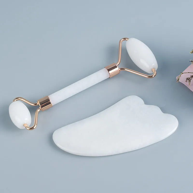 White jade double-headed facial roller and gua sha board set on a plain background.