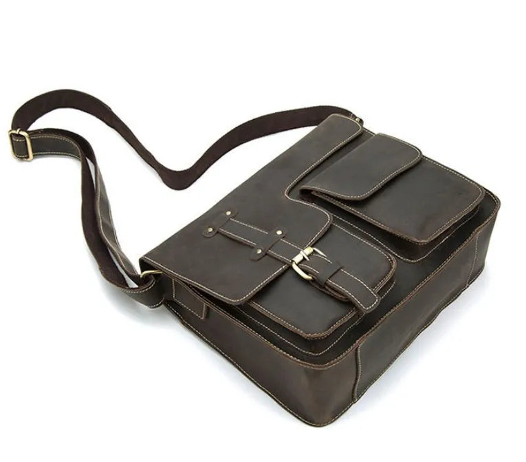 Brown full-grain leather vintage messenger bag with front flap, shown open to reveal internal laptop sleeve and pockets.