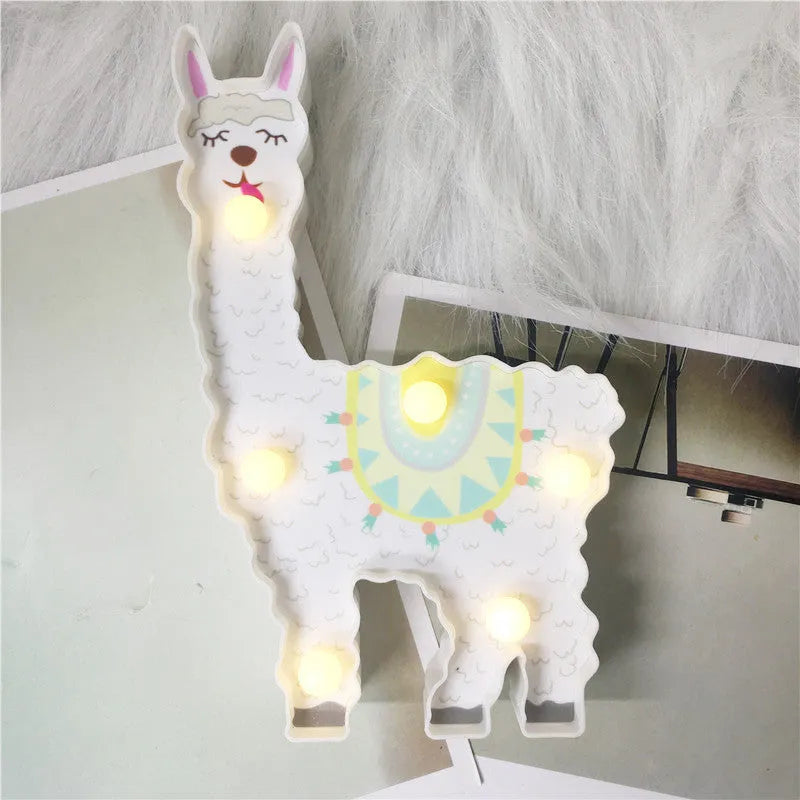 Alpaca night light in white, 19cm tall, with soft LED glow on a bedside table