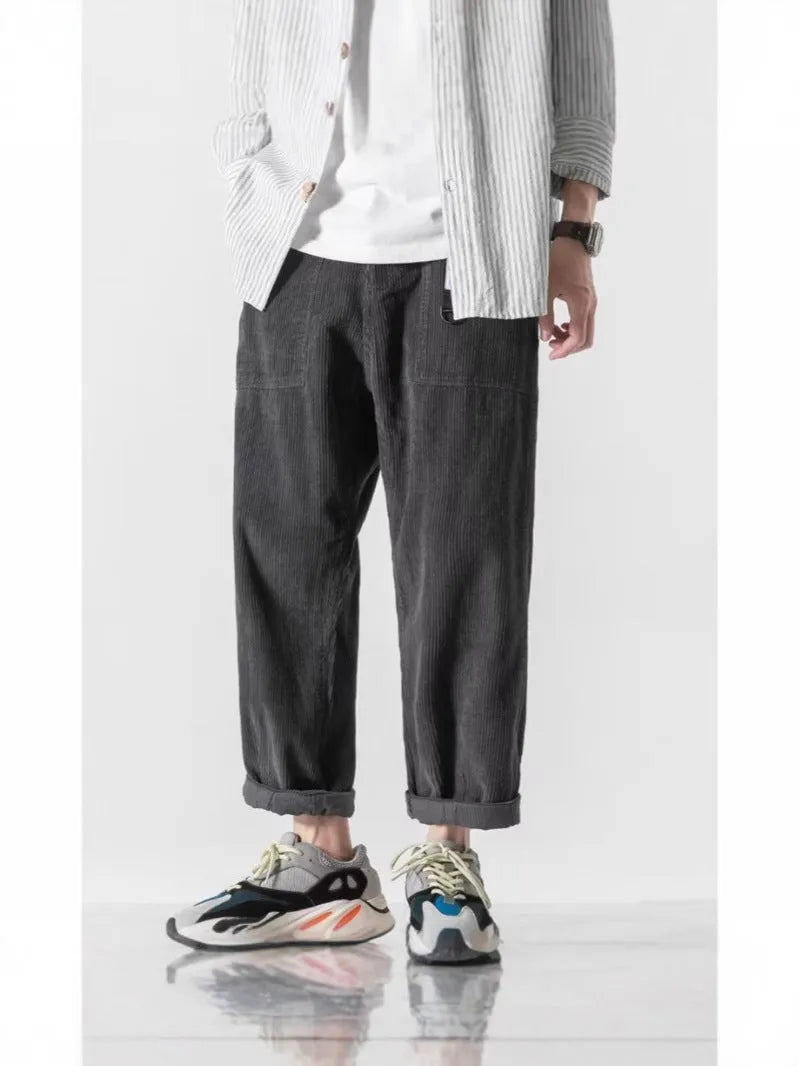 Man wearing loose straight leg casual trousers in dark grey, showing tapered fit and wide leg opening.