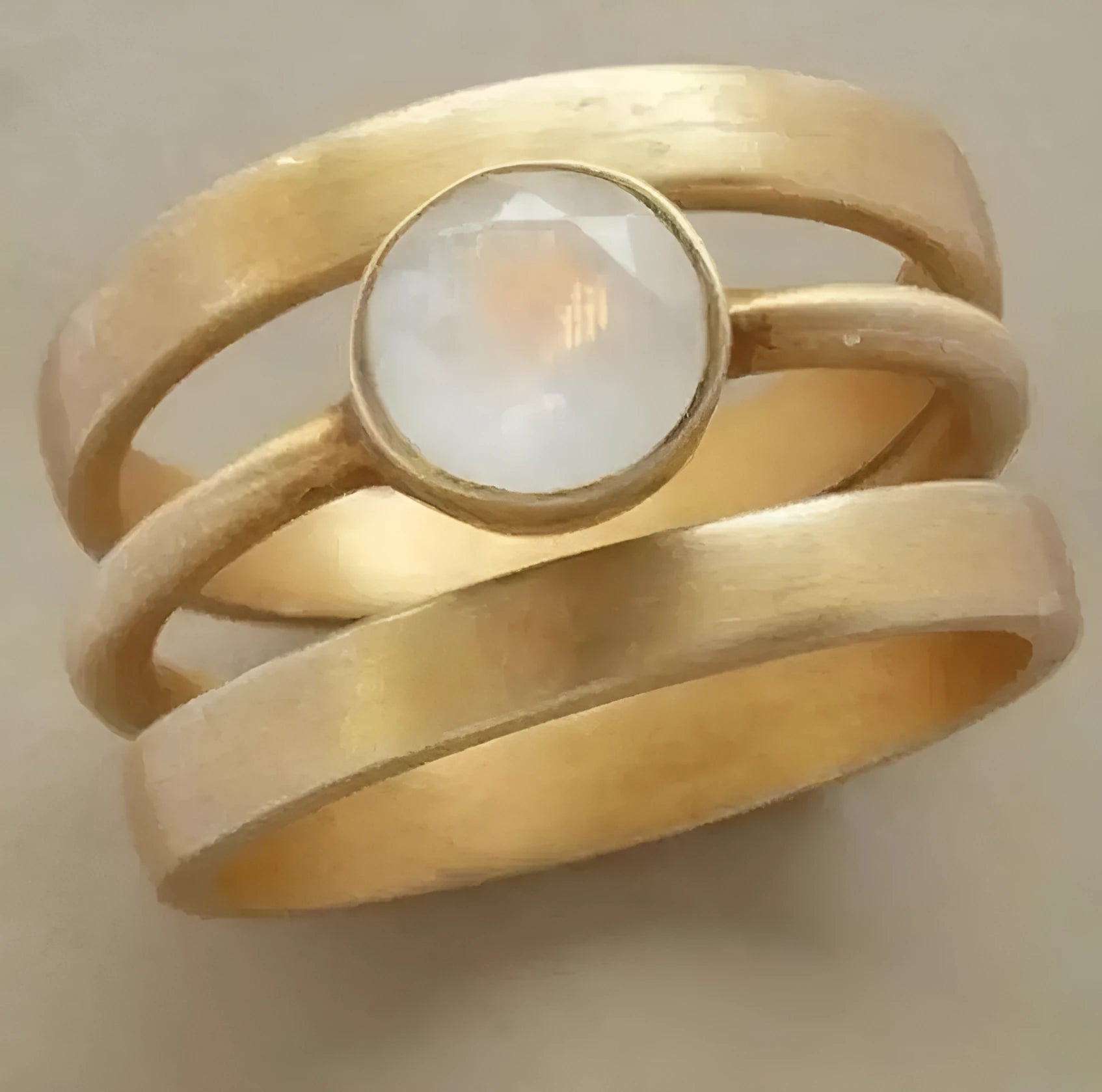 Gold geometric titanium steel ring with a white chalcedony stone inlaid in a hollow design on a finger.
