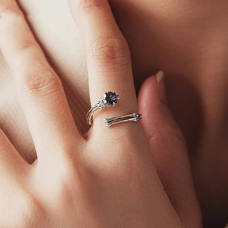 Adjustable silver skull hand ring with heart shaped base and pumpkin skull detail on white background
