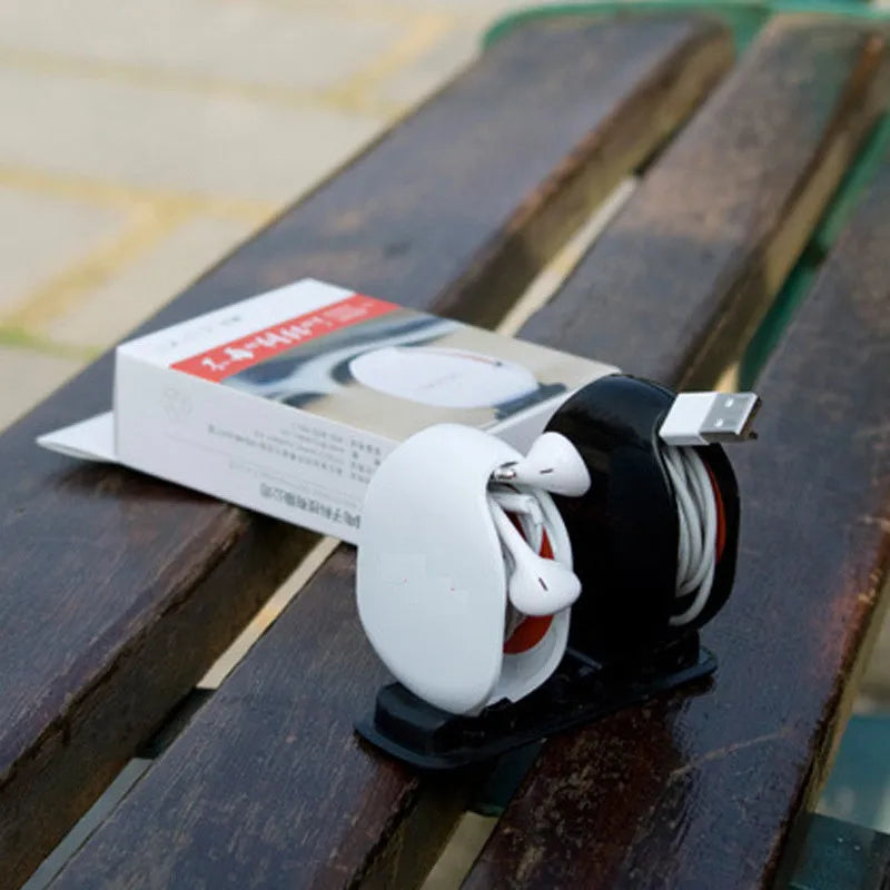 Compact automatic earphone winder in multiple colours on a grey background, showing extended cable.