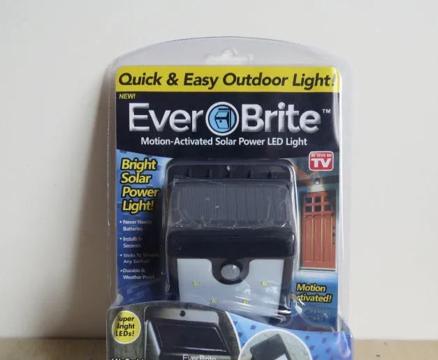 Four white rectangular solar-powered LED security lights with motion sensors mounted on an outdoor wall.